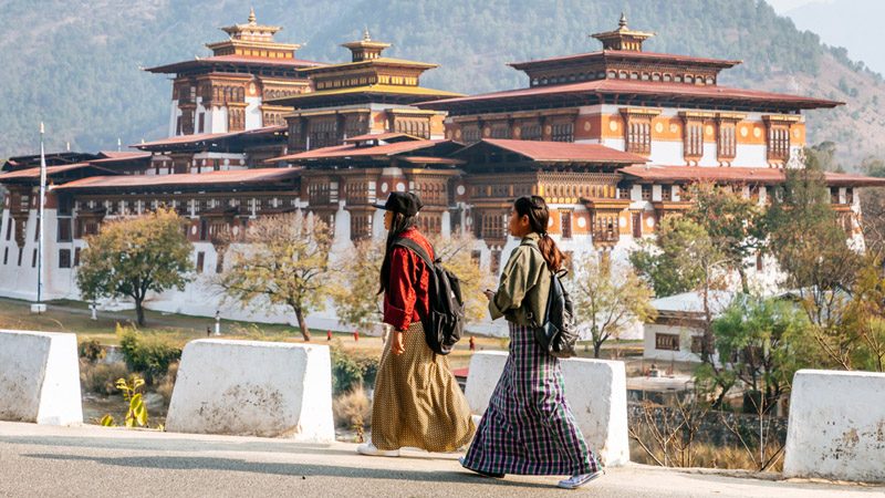 Two women are walking past Punakha Dzong